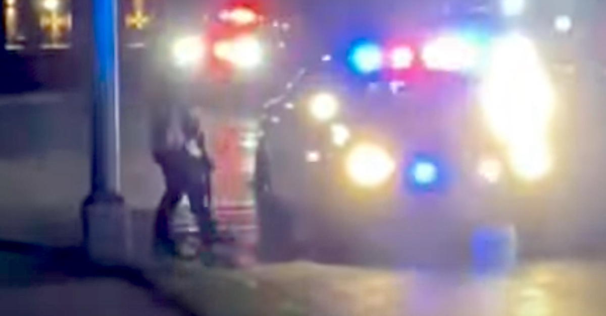A still frame from an evidence video shows the moment when Kenosha police officers began to pepper spray Kyle Rittenhouse to get him out of the road. They said he touched his rifle several times when he approached their squad car and that they were concerned he was a threat. (Image via the Law&Crime Network.)