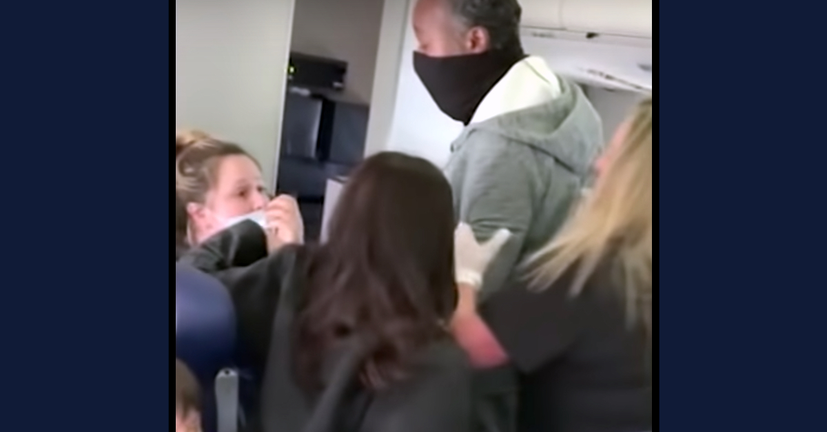 Vyvianna M. Quinonez (far left, seated) is confronted by a male passenger (center, standing) after beating a flight attendant (far right, standing, wearing dark clothes and holding onto the male's arm with a white sanitary glove over her hand). (Image via screengrab from KABC-TV/YouTube.)