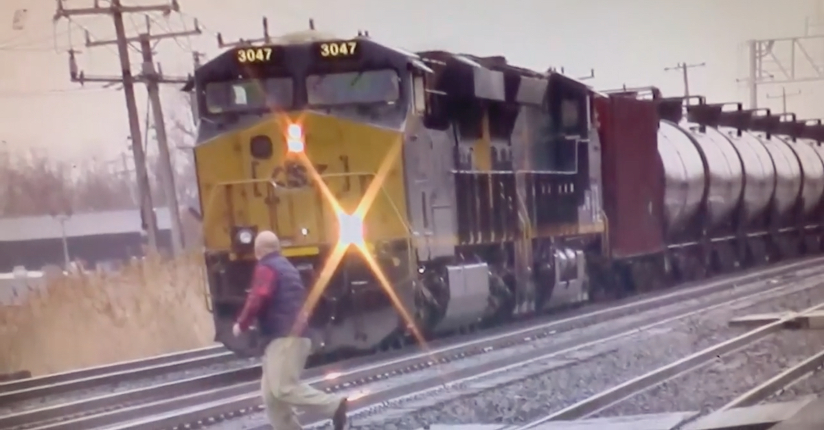 In an image captured by a railroad enthusiast, a man later identified as John L. Michalski runs in front of a CSX freight train. (Image via WIVB screengrab.)