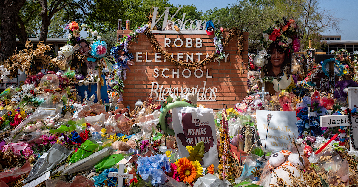 The Robb Elementary School sign is seen covered in flowers and gifts on June 17, 2022 in Uvalde, Texas. (Photo by Brandon Bell/Getty Images.)