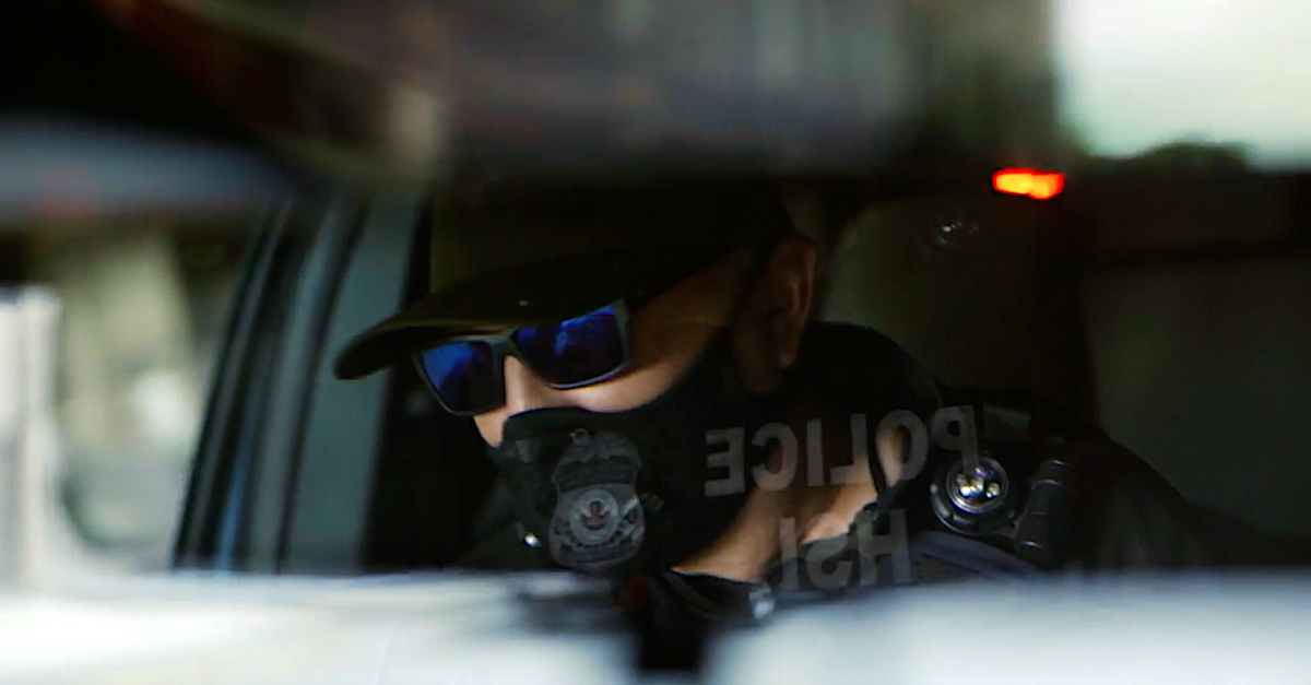 A screengrab shows a police officer wearing a face mask and sunglasses.