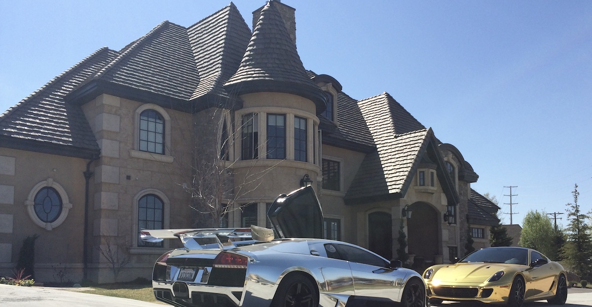 A Bugatti and a Ferrari parked outside a large home