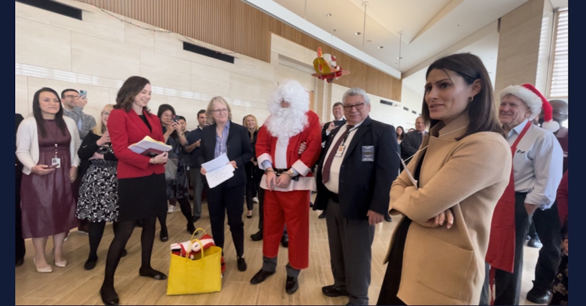 A judge dressed in a Santa Claus surrounded by other judges and court staff