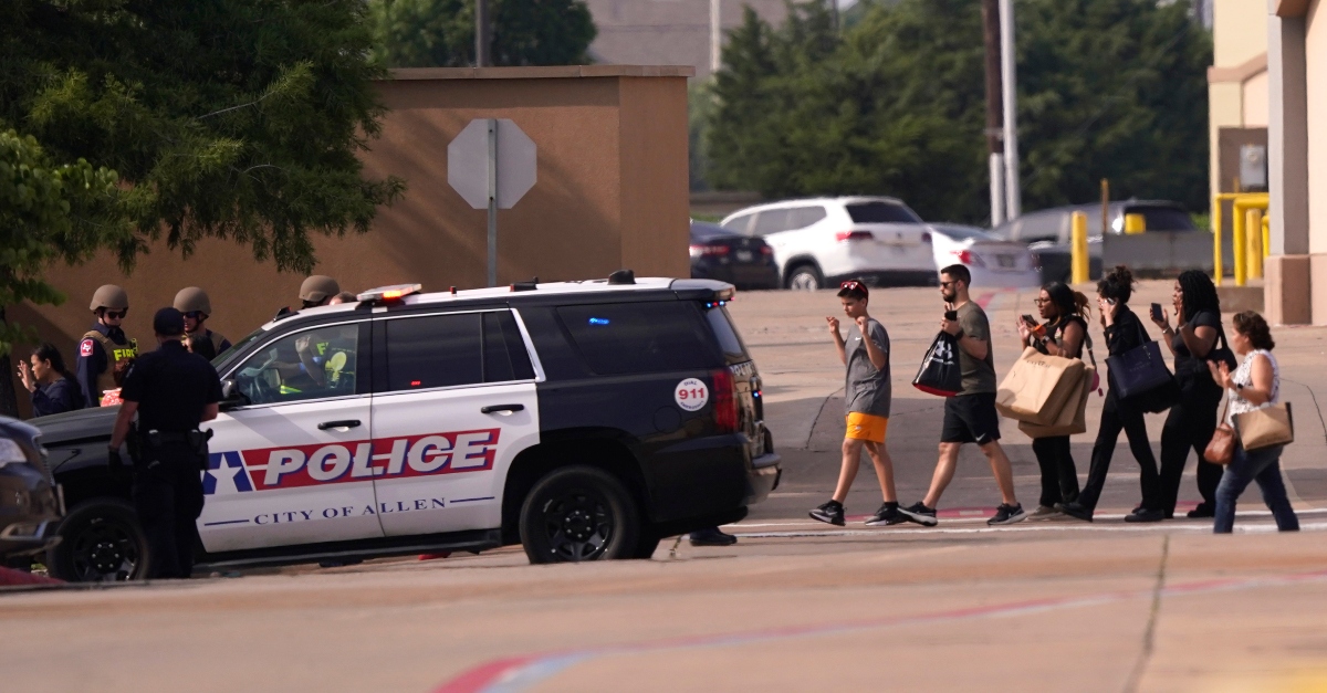 People raise their hands as they leave a shopping center following reports of a shooting, Saturday, May 6, 2023, in Allen, Texas. (AP Photo/LM Otero)